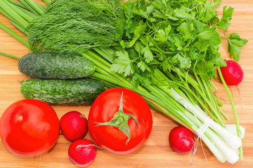 Top view of vegetables and greens on bamboo cutting board