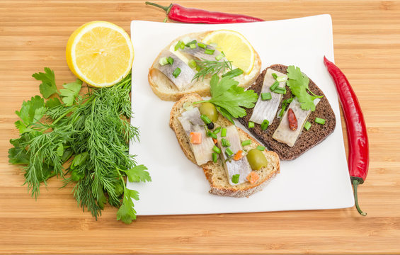 Three different open sandwiches with pickled herring fillet on dish