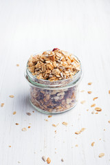 Granola in glass jar on the white wooden table. Shot at angle.