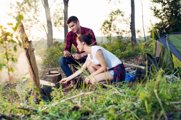 Young camping couple cooking meal