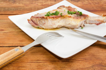 Grilled pork loin chop with fork and knife closeup