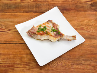 Grilled pork loin chop on dish on rustic table