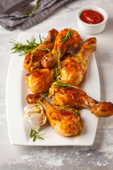 Grilled spicy chicken legs baked with garlic, rosemary and thyme on white background.