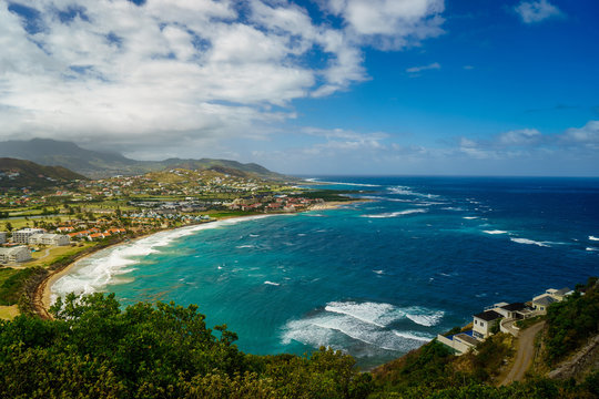 A view over St. Kitts Island with residential area and beaces on the foreground and lush green hills on the background