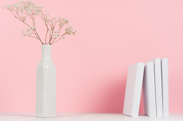 Small dried flowers in elegant vase and white books on wood table and soft pastel pink background, copy space. Fashion home interior.