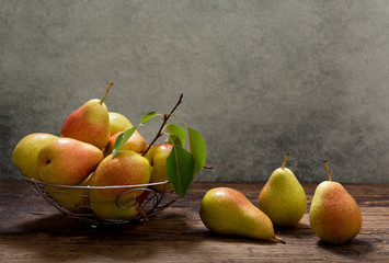 pears with leaves in a basket on wooden table