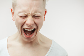 Closeup dramatic emotional portrait of desperate enraged young man, screaming loudly, losing his...