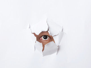 Hole torn in paper with the eye of man