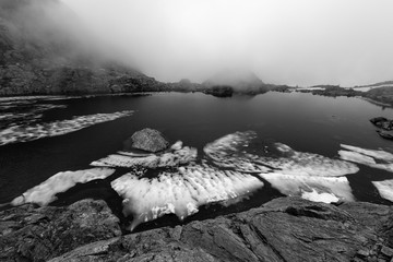 Black and white photo of pieces of ice in an alpine lake