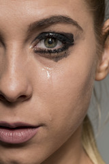 Sad crying girl looking into camera with smeared make-up