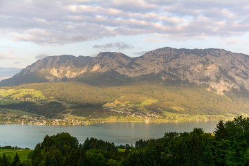 View to lake Attersee with green pasture meadows and Alps mountain range near Nussdorf Salzburg, Austria