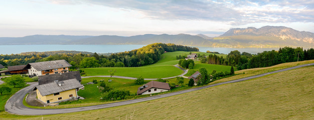 View to lake Attersee with green pasture meadows and Alps mountain range near Nussdorf Salzburg,...