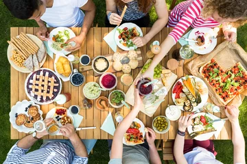 Fototapeten Draufsicht auf Leute, die Pizza, Gebäck und Salat während der Grillparty im Garten essen © Photographee.eu