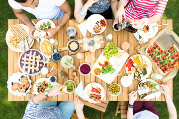 Top view on garden table with salad, fruits and pizza during outdoor meeting of friends