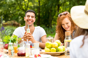 Smiling friends drinking water and eating food during birthday party in the park © Photographee.eu