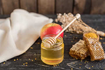 Beautiful transparent honey in bank, honeycombs and pollen on a wooden table. It can be used as a background