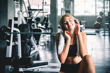 Fototapeta na wymiar woman listening to music during workout and take a rest at sport gym for relaxation with happy and smile