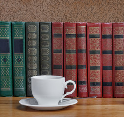 Naklejka premium Hot cup of fresh coffee on the wooden table with books