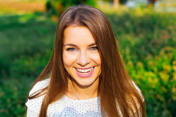 Close-up face of a girl who happily smiles against a background of green grass