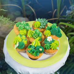 detailed representation of cupcakes decorated with cream, like cacti and succulents, against the...