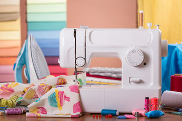 Sewing machine in work and accessories, on background of fabric samples