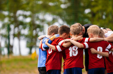 Boys football team with coach. Youth soccer team huddle with coach. Motivation talk, pep talk before the match. Young football soccer players in jersey colorful sportswear