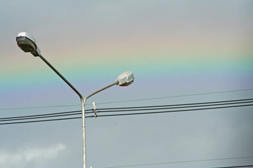 Street lampposts and rainbow on sky background