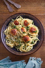 Pasta with meatballs and spinach. Spaghetti with meatballs in bowl on wooden table. overhead, vertical