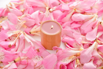 Pile of pink tropical petals and candle 