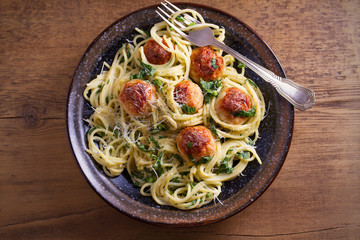 Pasta with meatballs and spinach. Spaghetti with meatballs in bowl on wooden table. overhead, horizontal