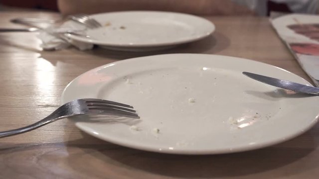 Close up of empty dirty dish with fork and napkin left on table