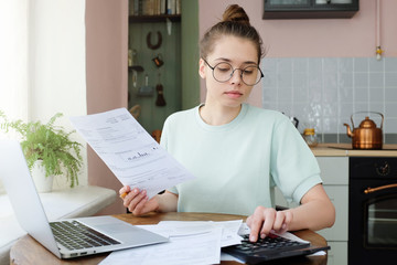 Yong woman budgeting, managing utilities expences, writing financial plan, analyzing her spendings