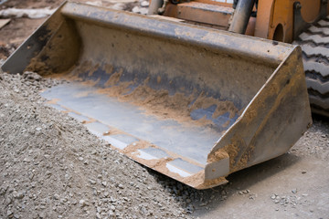 The blade of a bulldozer raking gravel