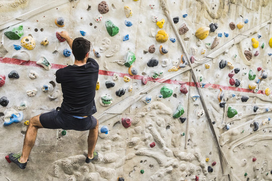 Man practicing rock climbing on artificial wall indoors. Active lifestyle and bouldering concept..