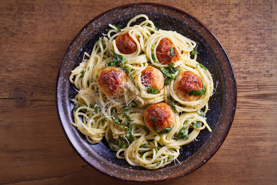 Pasta with meatballs and spinach. Spaghetti with meatballs in bowl on wooden table. overhead, horizontal