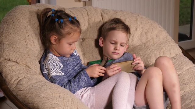Sit on a comfortable chair children play mobile smart phone games and watch cartoons at home