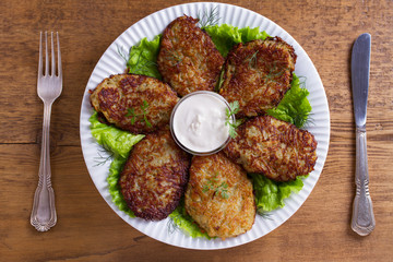 Potato pancakes with sour cream or yogurt. Vegetable fritters, latkes, draniki. View from above, top studio shot