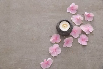  Pile of Pink hydrangea petals with candle in stone bowl on gray background © Mee Ting