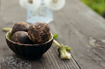 Vegan raw balls with nuts, date and carob . Fresh no-bake and no cooking dessert on wooden table with summer flowers.