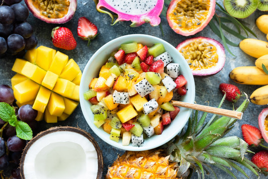Tropical fruit salad with mango and pitaya in bowl. Healthy salad. Mango, coconut, pineapple, pitaya, mango and passion fruit salad