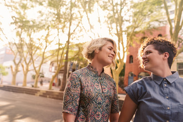 Smiling young lesbian couple walking together on a city street