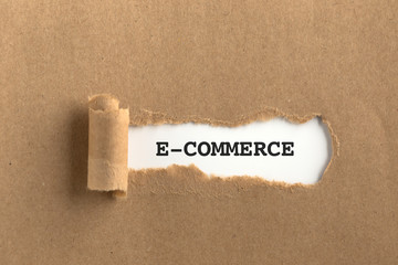 The text E-COMMERCE behind torn brown paper
