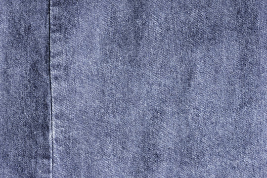 Old blue denim jeans texture or background with visible fibers and seam