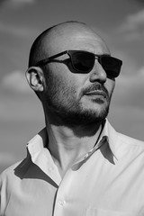 portrait of a bearded man wearing sunglasses against the sky.
