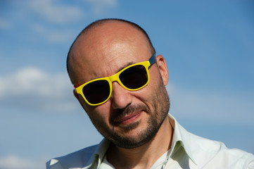 portrait of a businessman in modern sunglasses against a blue sky background.