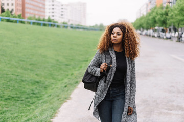 junge frau mit tasche geht an einer straße in der stadt entlang