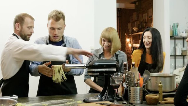 Man making pasta from dough using pasta machine at culinary class. 4K