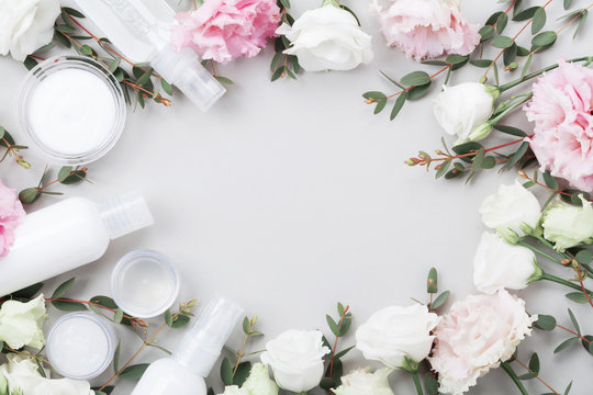 Frame from natural cosmetic and flowers on pastel table top view. Flat lay style.