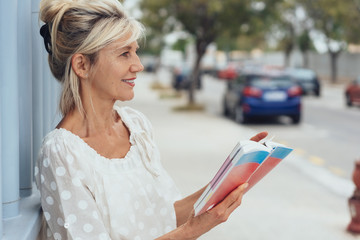 attraktive ältere dame besichtigt eine stadt und blättert im reiseführer