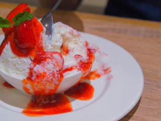  stainless spoon scooping snowflake Frozen cow's milk,  Bingsu  and topped with strawberry syrup.dessert of Korea style